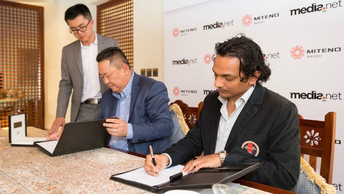 Divyank Turakhia (R) and Zhang Zhiyong (C) sign the acquisition agreement