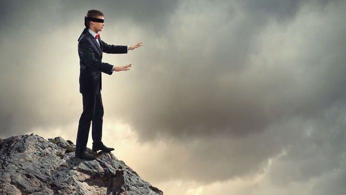 21167907 - image of businessman in blindfold standing on edge of mountain